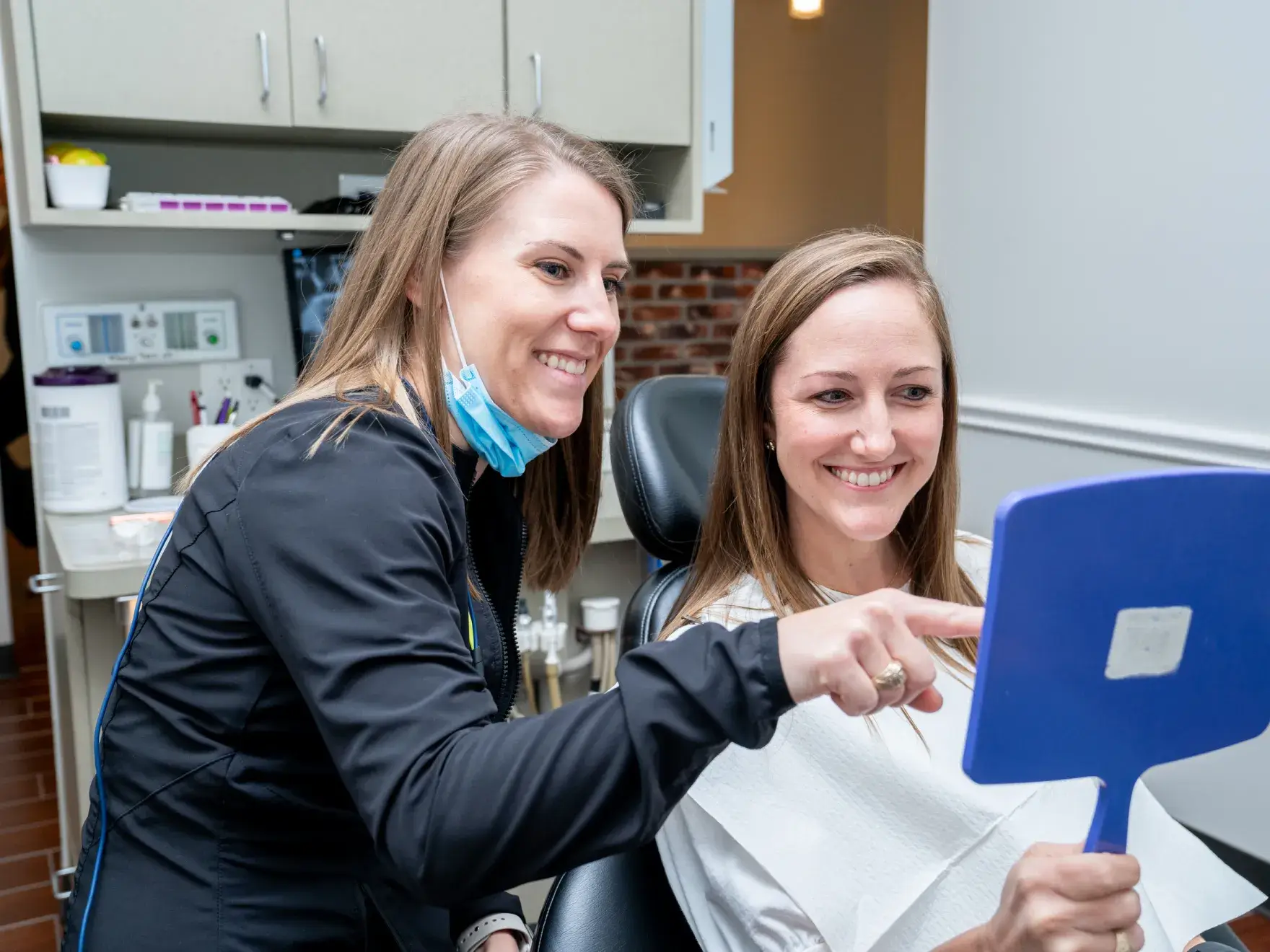 a woman sitting in a dentist chair holding a blue spatula